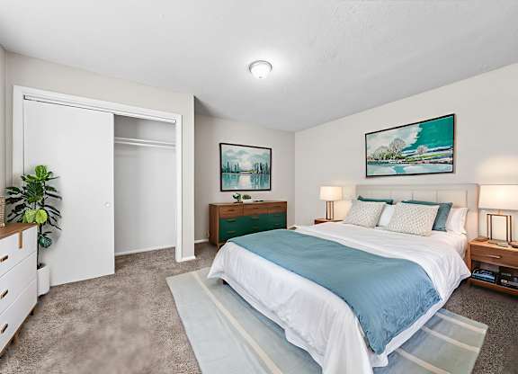 A bedroom with a large bed and a painting on the wall.