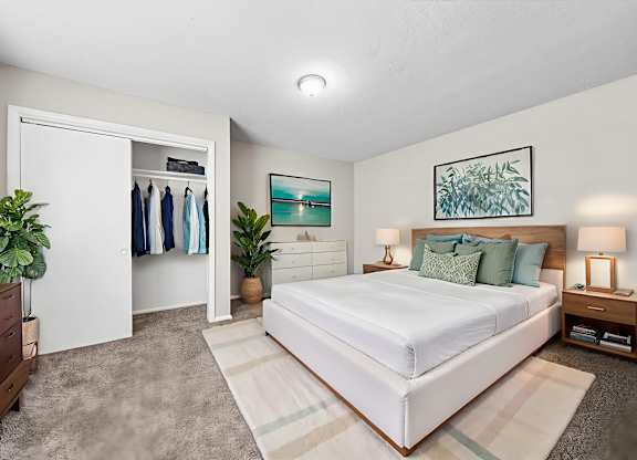 A bedroom with a large bed, a dresser, and a painting on the wall.