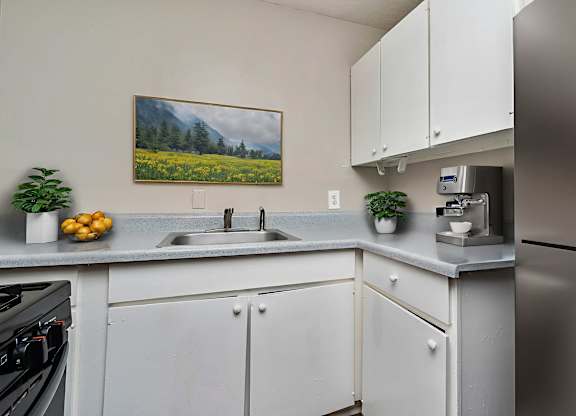 A kitchen with a painting of a field of flowers on the wall.