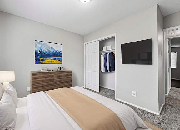 A bedroom with a bed, a dresser, a mirror, and a painting on the wall.