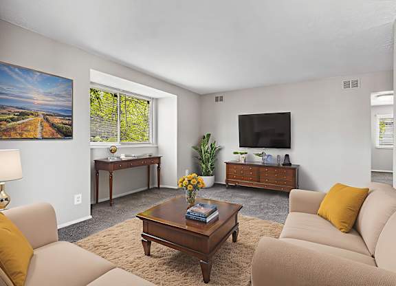 A living room with a brown coffee table and beige couches.