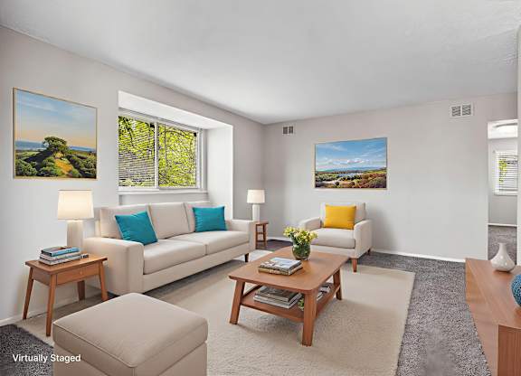 A living room with a white couch, a brown coffee table, and two pictures on the wall.
