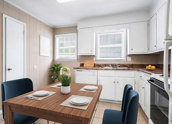 A kitchen with a table set for two with a plant on it.