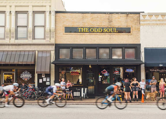 A group of people riding bikes in front of a store called The Odd Soul.