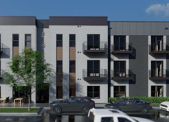 A modern apartment complex with cars parked in front.