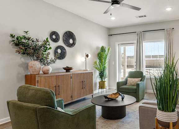 A living room with a green chair, a brown sofa, and a ceiling fan.