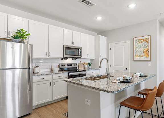 A kitchen with a stainless steel refrigerator, a microwave, and a sink.