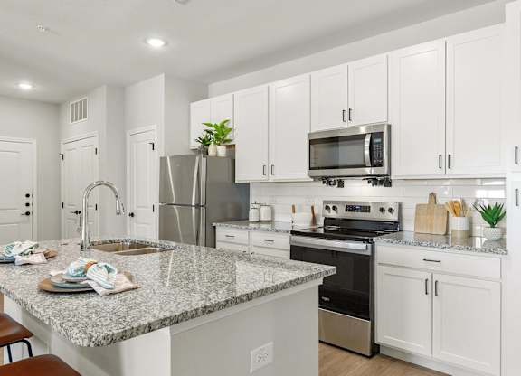 A modern kitchen with white cabinets and a granite countertop.
