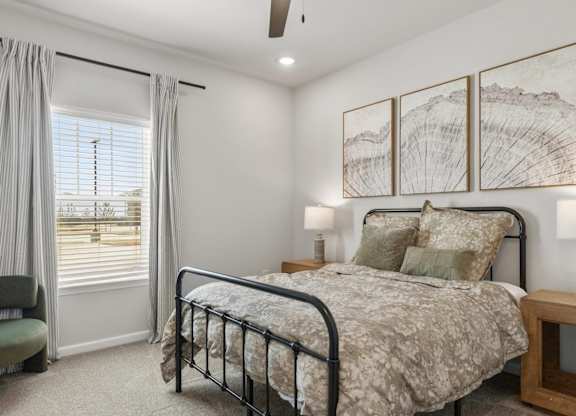 A bedroom with a bed, chair, and a window with curtains.