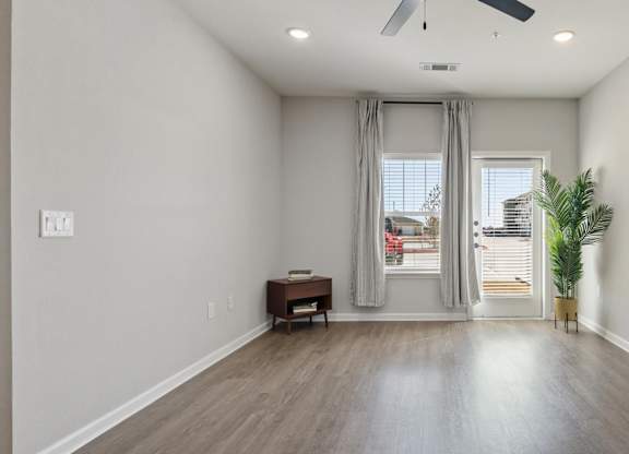A room with a ceiling fan and a window with curtains.