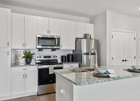 A modern kitchen with white cabinets and stainless steel appliances.