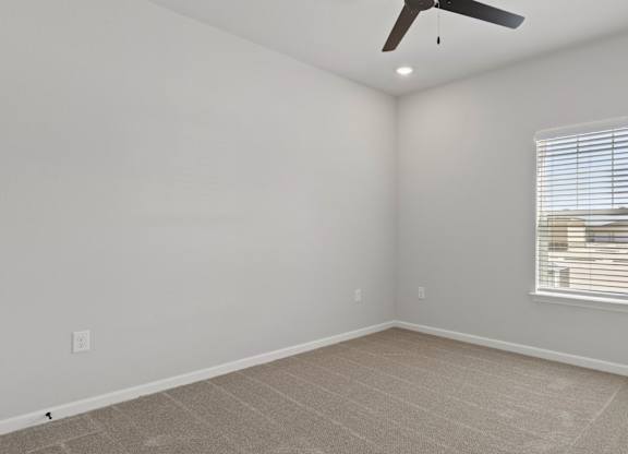 A room with a ceiling fan and a window with blinds.