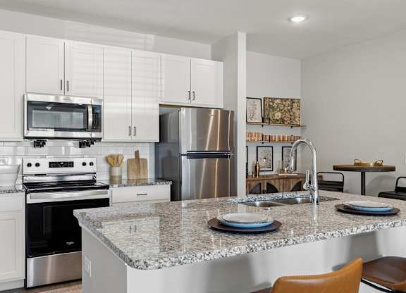 A modern kitchen with a granite countertop and stainless steel appliances.