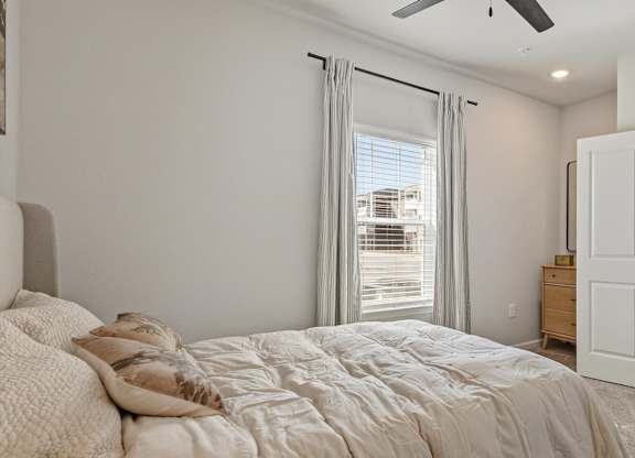 A bedroom with a large bed and a ceiling fan.
