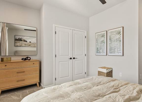 A bedroom with a bed, dresser, and two framed pictures on the wall.