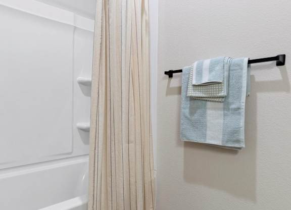 A white bathroom with a towel rack and a shower curtain.