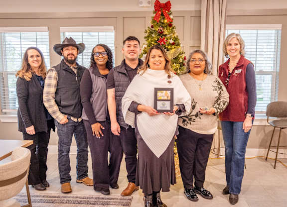 A group of people are posing for a photo in a room with a Christmas tree in the background.