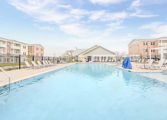 A large swimming pool in front of a building with a blue umbrella.