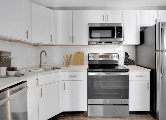 a white kitchen with stainless steel appliances and white cabinets at Station JTown, Louisville, Kentucky