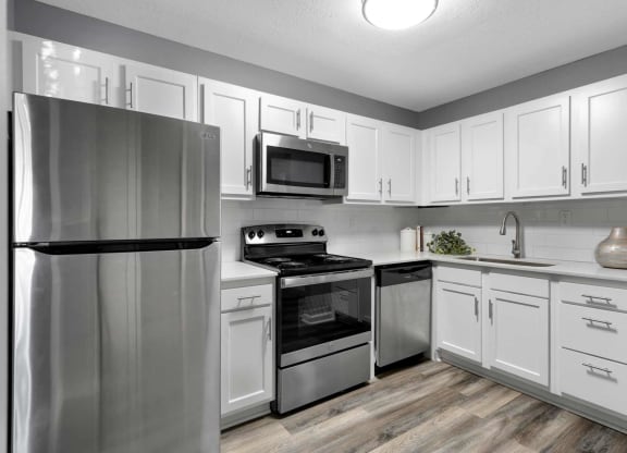 a kitchen with stainless steel appliances and white cabinets  at Station JTown, Louisville, KY, 40299