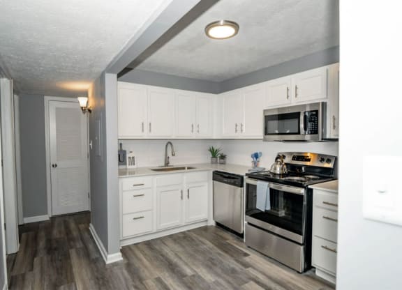 a kitchen with white cabinets and stainless steel appliances at Station JTown, Kentucky, 40299