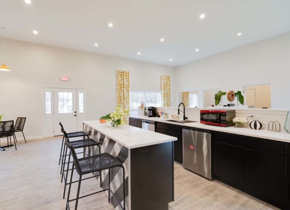 a kitchen with a long counter and black and white chairs at Station JTown, Kentucky, 40299
