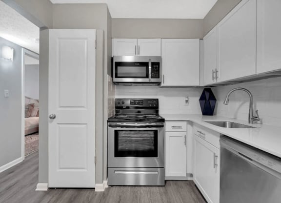 Louisville, KY Pet-Friendly Apartments - Enclave At Breckenridge - Kitchen With Hardwood Floor, White Cabinets, Granite Countertop, Stainless-Steel Appliances, And Pantry.
