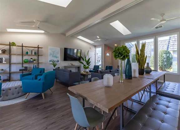 A modern living room with a large wooden table and blue chairs.