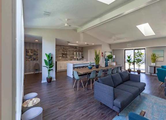 A living room with a grey couch and a dining table with chairs.