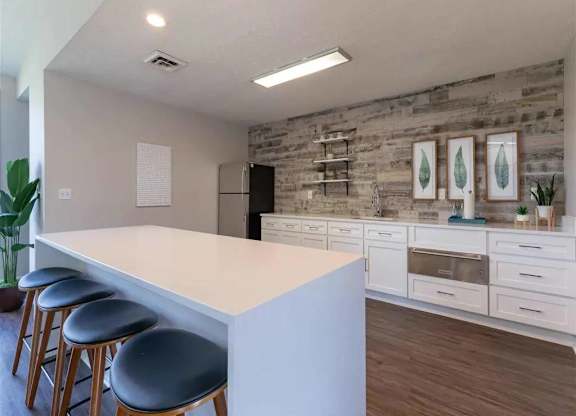 A kitchen with a white countertop and bar stools.