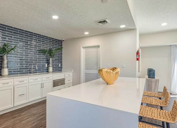 A kitchen with white cabinets and a blue backsplash.