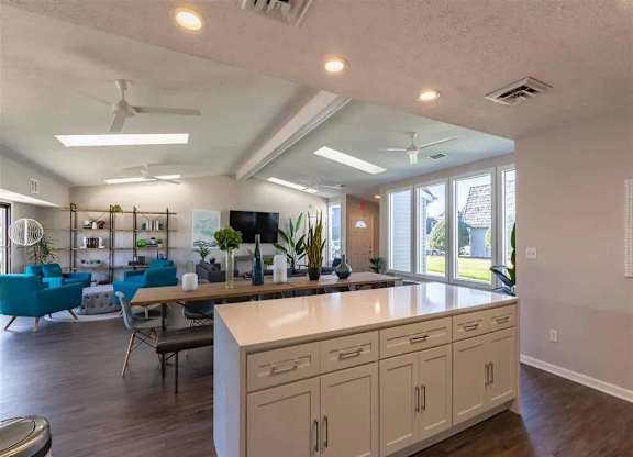A kitchen with a white counter and blue chairs.