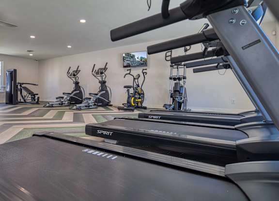 A treadmill in a gym with other exercise equipment.