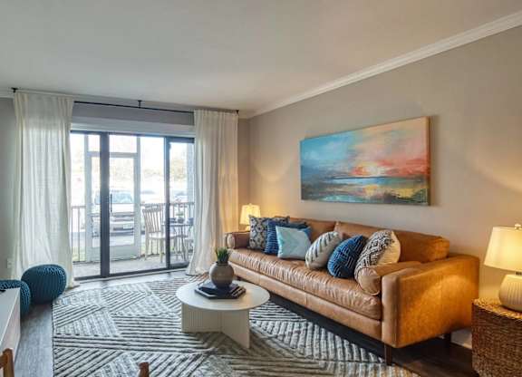 A living room with a brown couch, a television, and a painting on the wall.