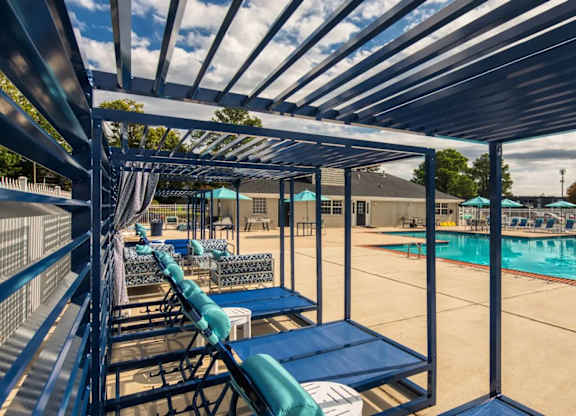 A poolside area with sun loungers and a shaded roof.