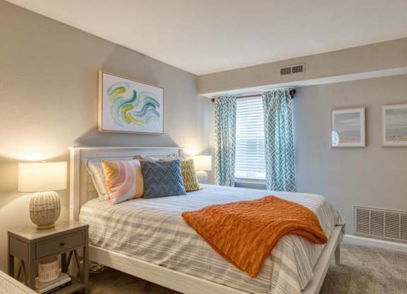 A bedroom with a bed, nightstand, and a painting on the wall.