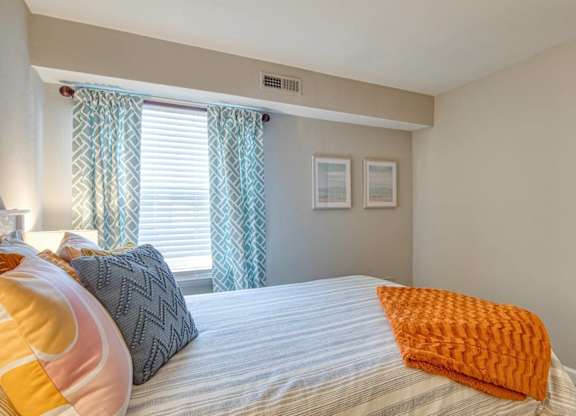 A bedroom with a bed, pillows, and a window with curtains.
