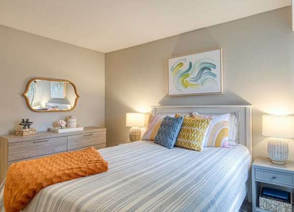 A bedroom with a bed, nightstand, and a painting on the wall.