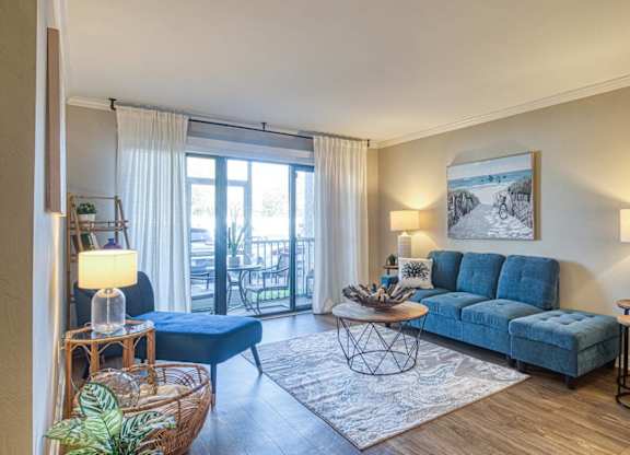 A living room with a blue sofa and a large window.