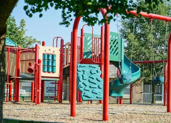 A playground with a red frame and a green slide.