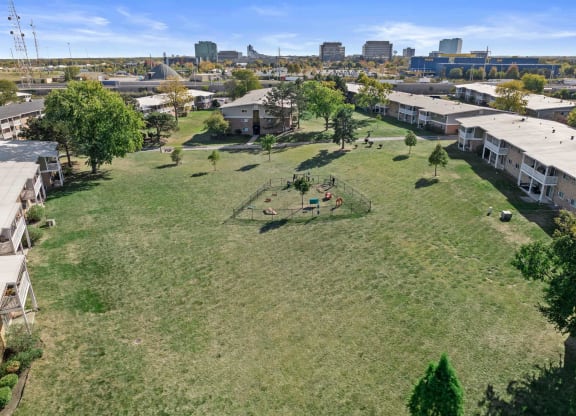 an aerial view of a park with houses and a city in the background
