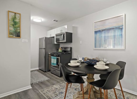 a kitchen with a table and chairs and a stainless steel refrigerator