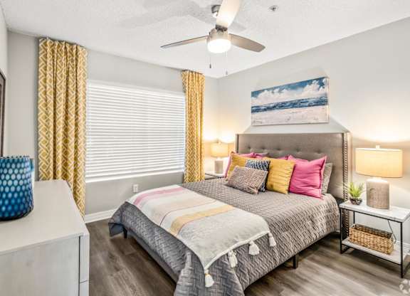 A bedroom with a bed, a nightstand, and a ceiling fan.at Coastline Apartments, Florida  