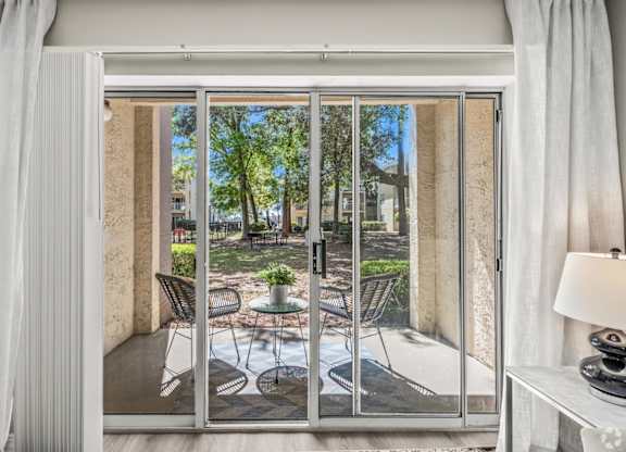 A patio with a table and chairs is visible through a sliding glass door.at Coastline Apartments, Fort Walton Beach, FL  