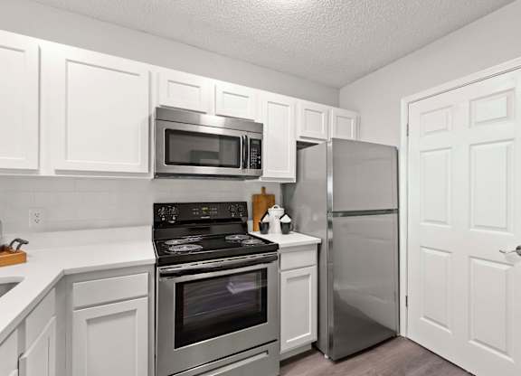 A kitchen with white cabinets and stainless steel appliances.at Coastline Apartments, Florida, 32547 