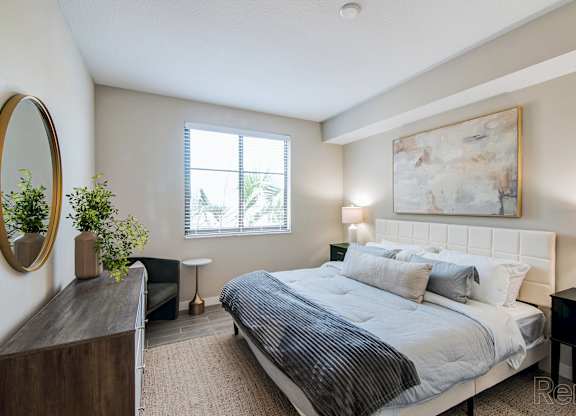 A bedroom with a large bed, a mirror, and a painting on the wall.