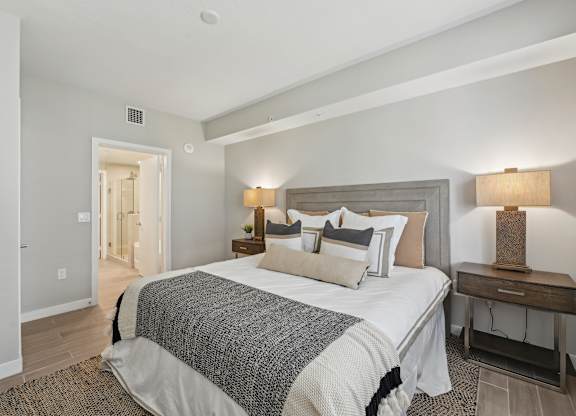 A bedroom with a large bed and a nightstand with a lamp.
