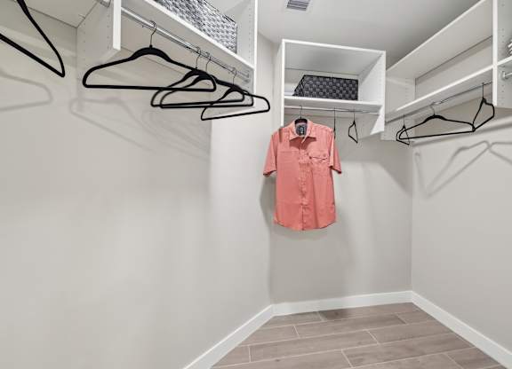A pink shirt hanging on a hanger in a white closet.