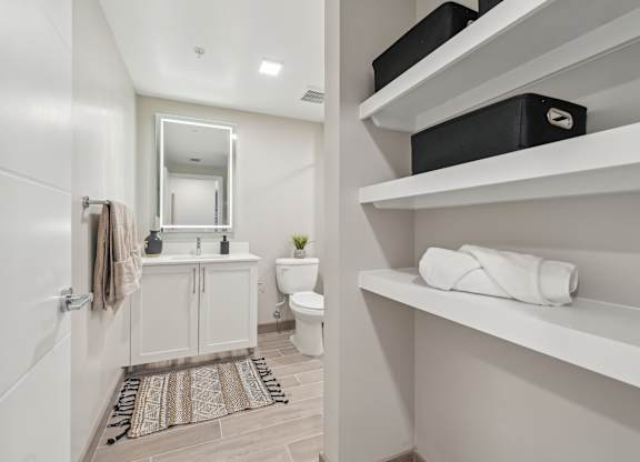 A bathroom with a toilet, sink, and mirror.