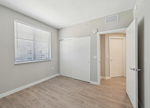 A room with a white door and a window with blinds.
